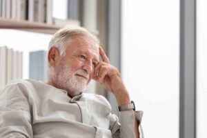 thinking senior man sits on a couch in the living room, elderly man thinks and sit on the sofa