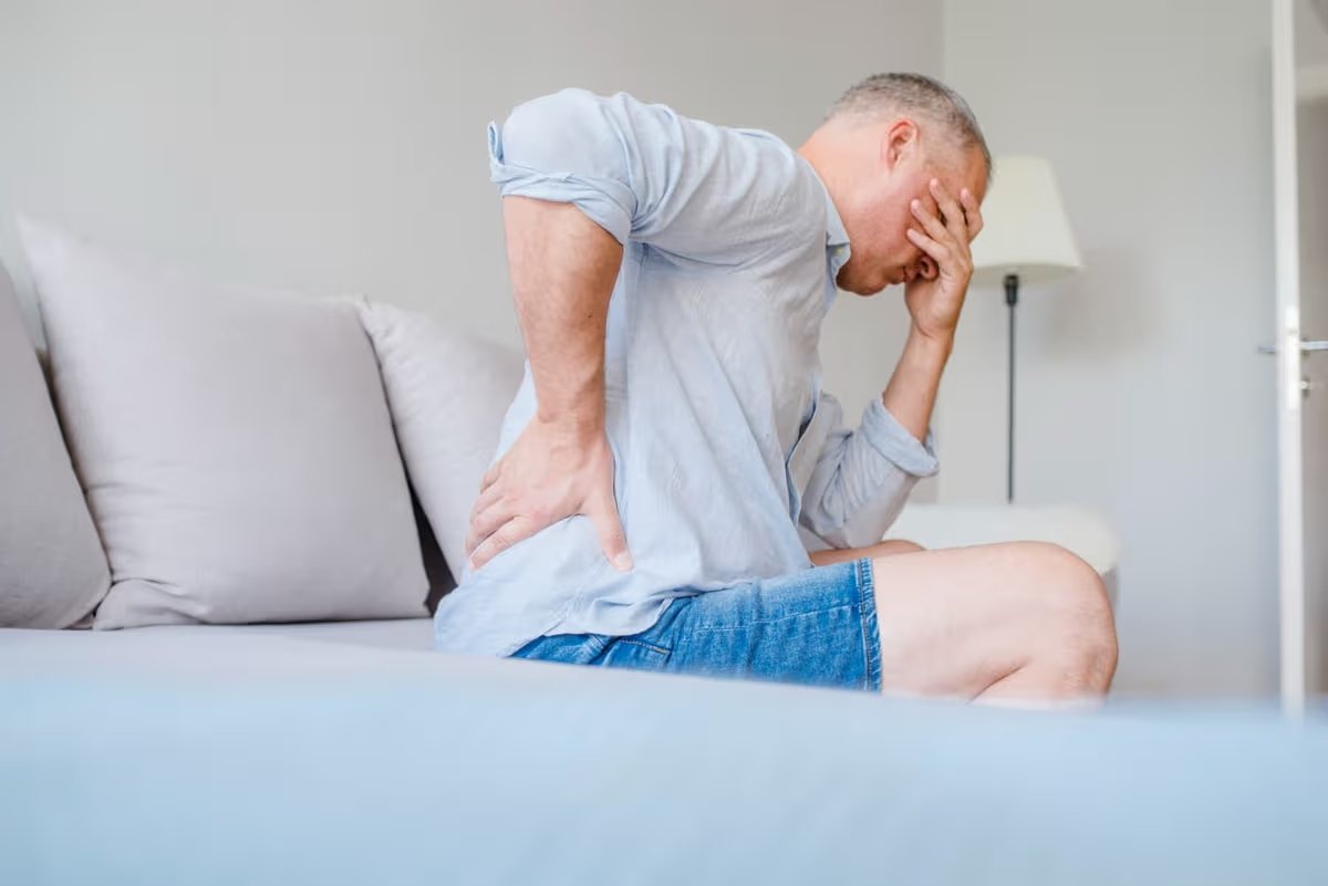 man suffering from back pain at home